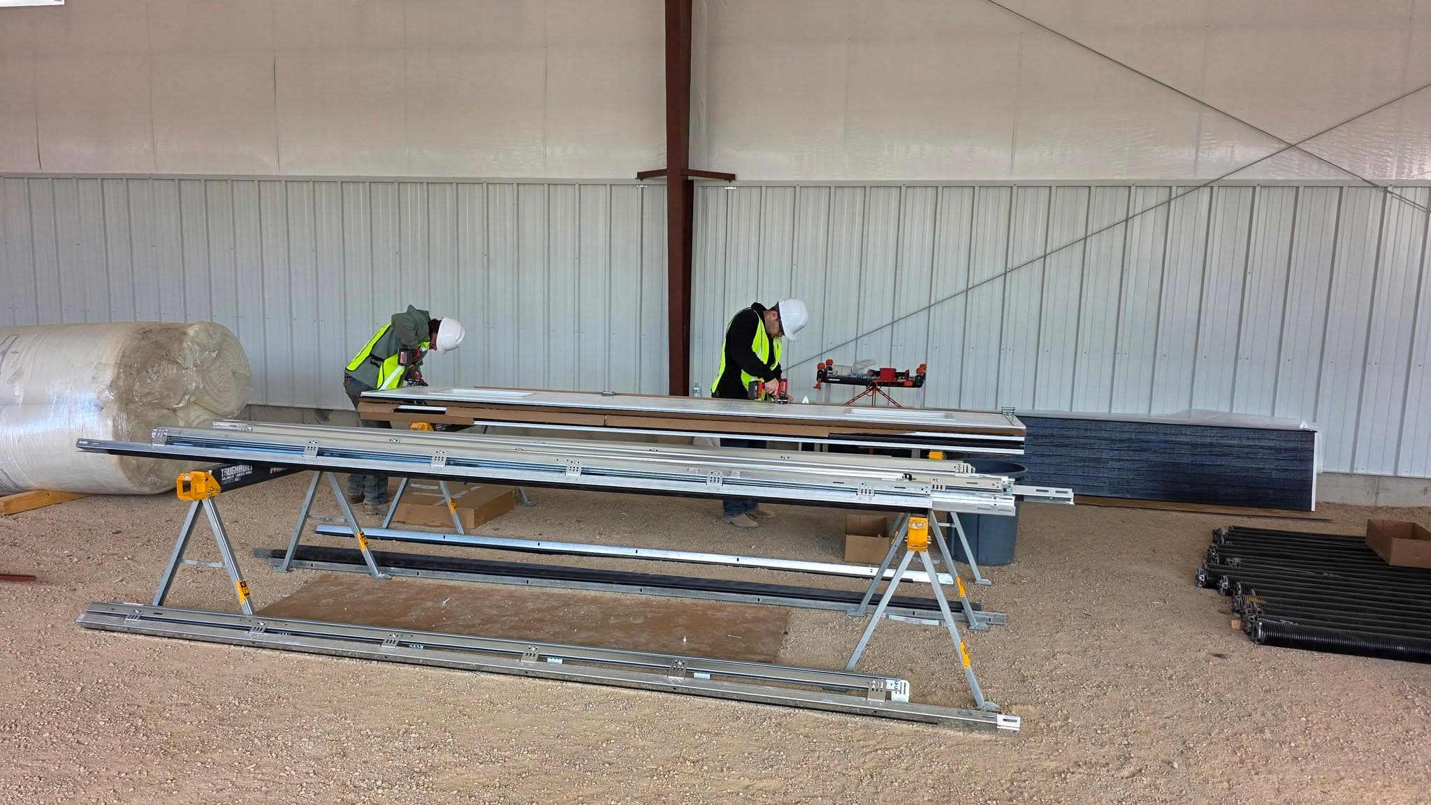 Workers in safety vests measuring and cutting metal roofing panels