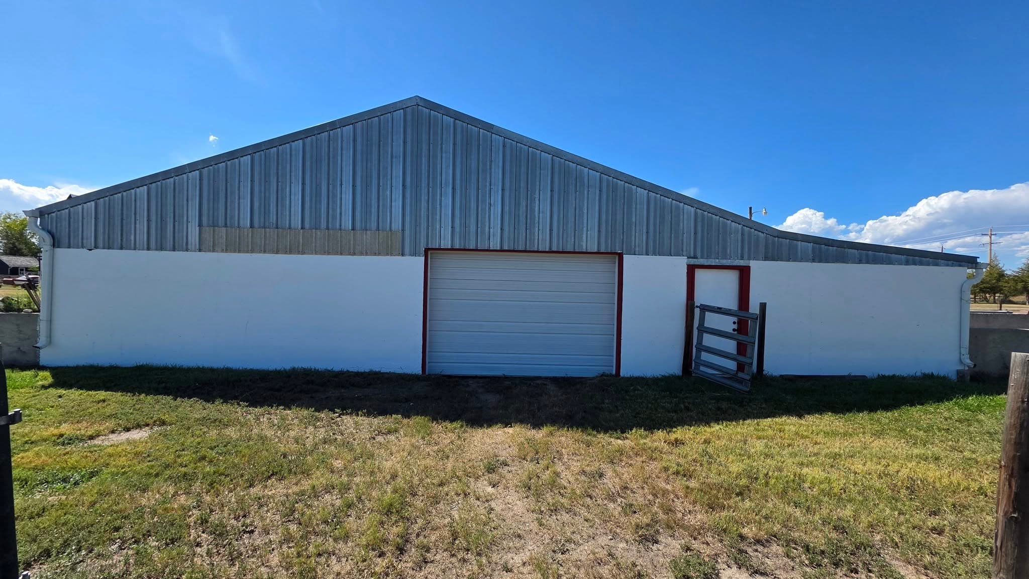 White and gray metal building with pitched roof and garage door