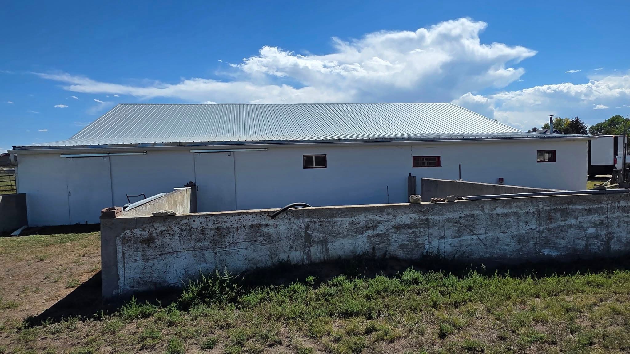 Long white metal building with metal roof against a cloudy sky