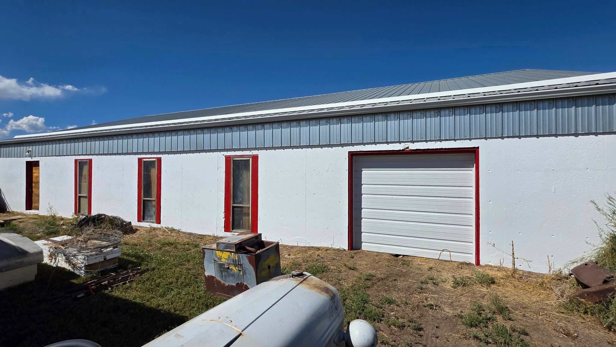 White metal building with red-trimmed doors against blue sky