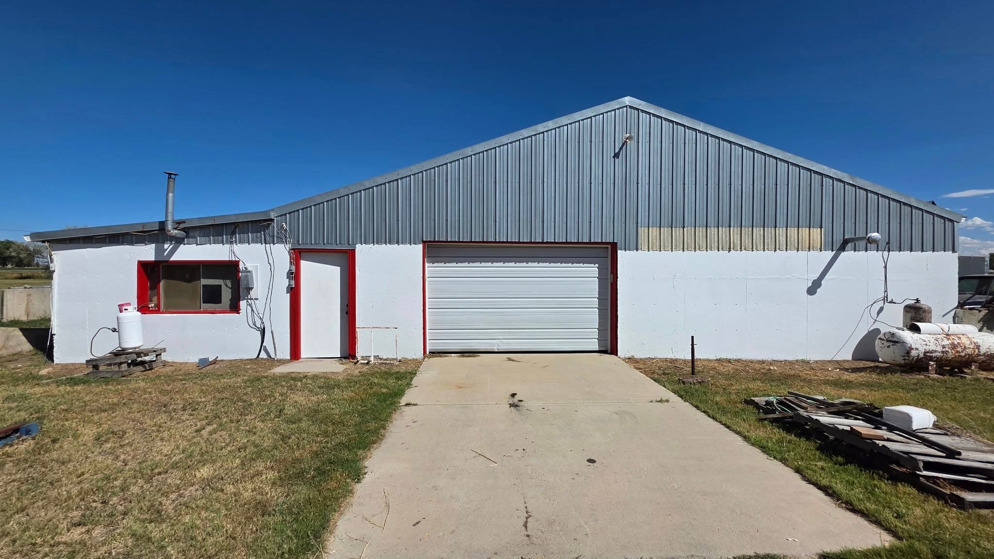 Industrial metal building with garage and red entrance door