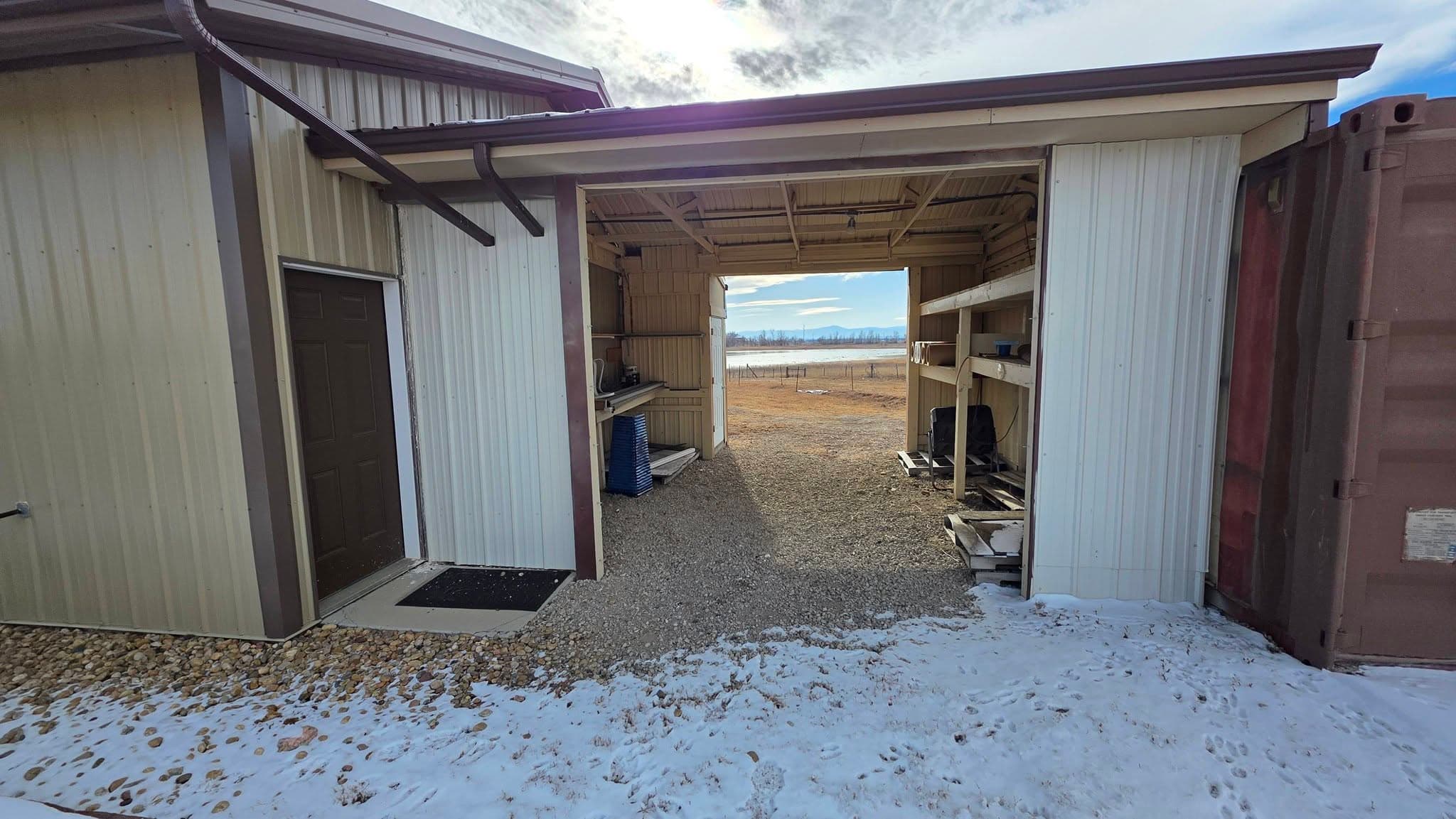 Interior of a metal building opening onto open Colorado land