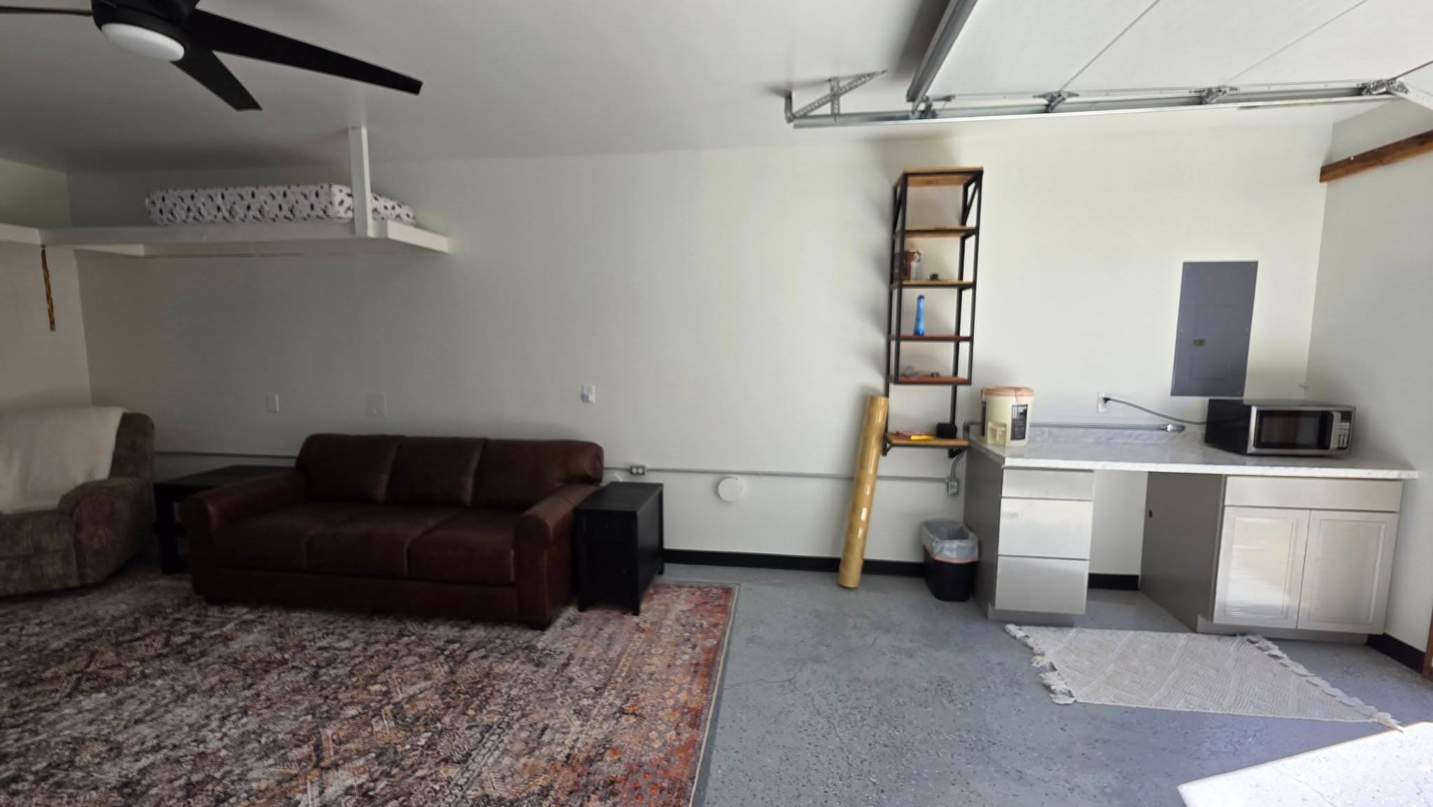 Finished garage interior with ceiling fans, couch, and flooring